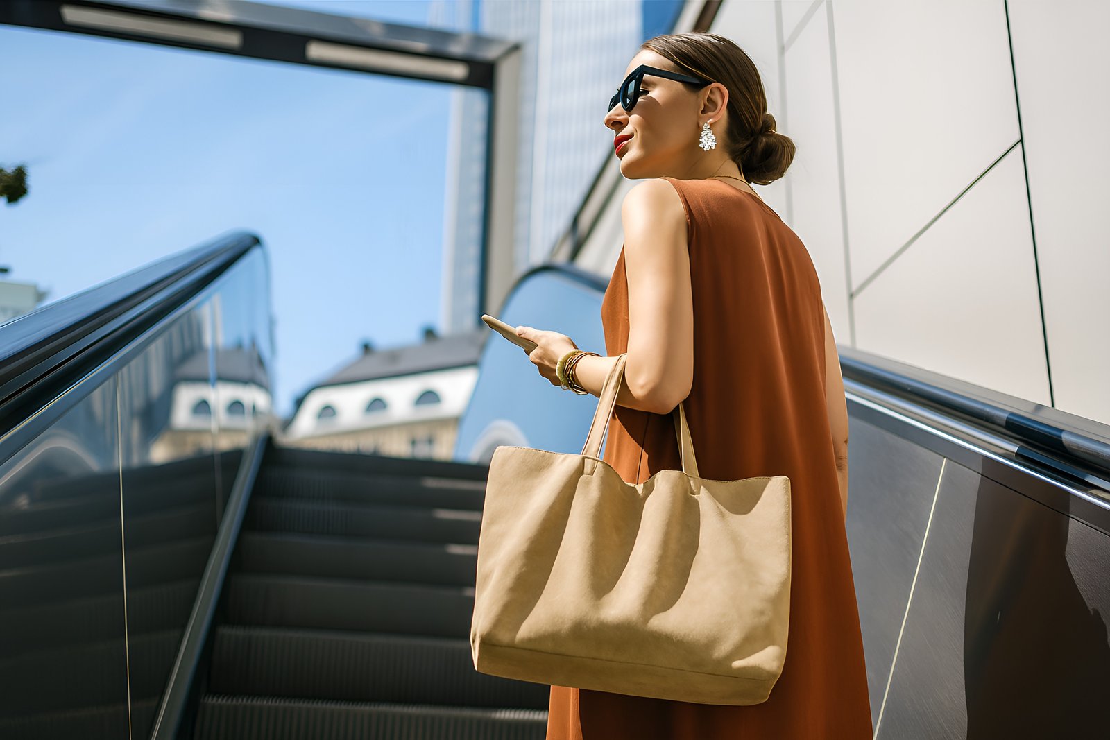 Elegant Woman with Stylish Accessories Riding Outdoor Escalator on a Bright Day
