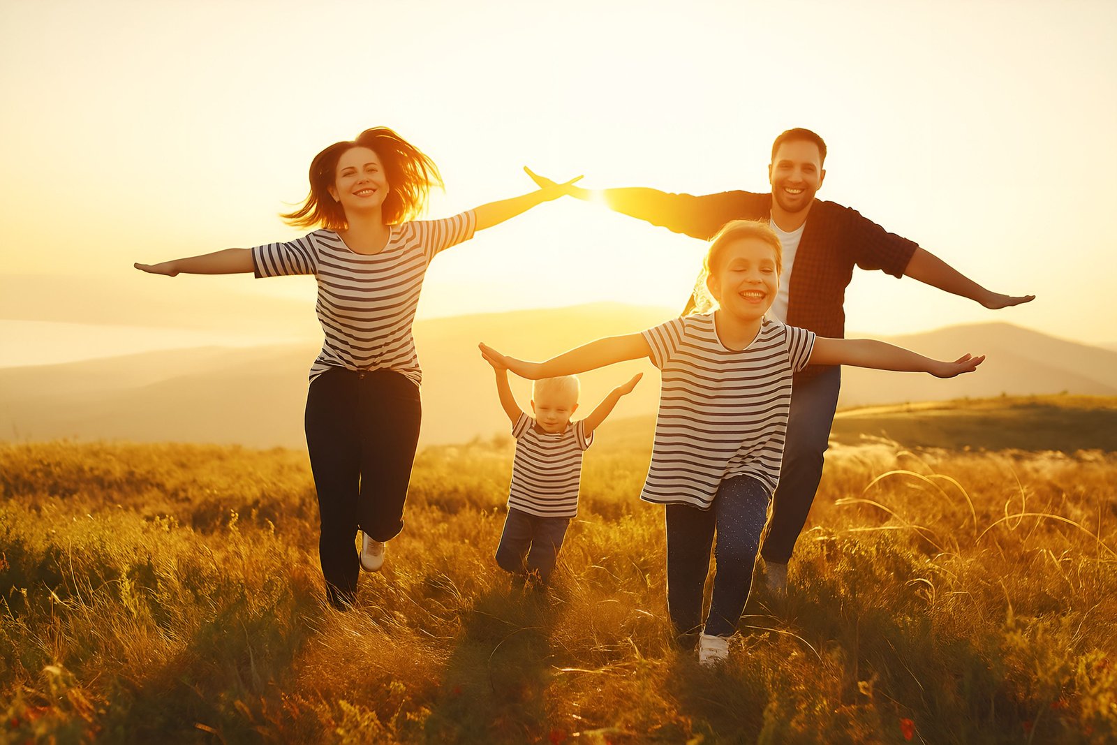 Happy Family Playing Together Outdoors in a Sunny Field at Sunset