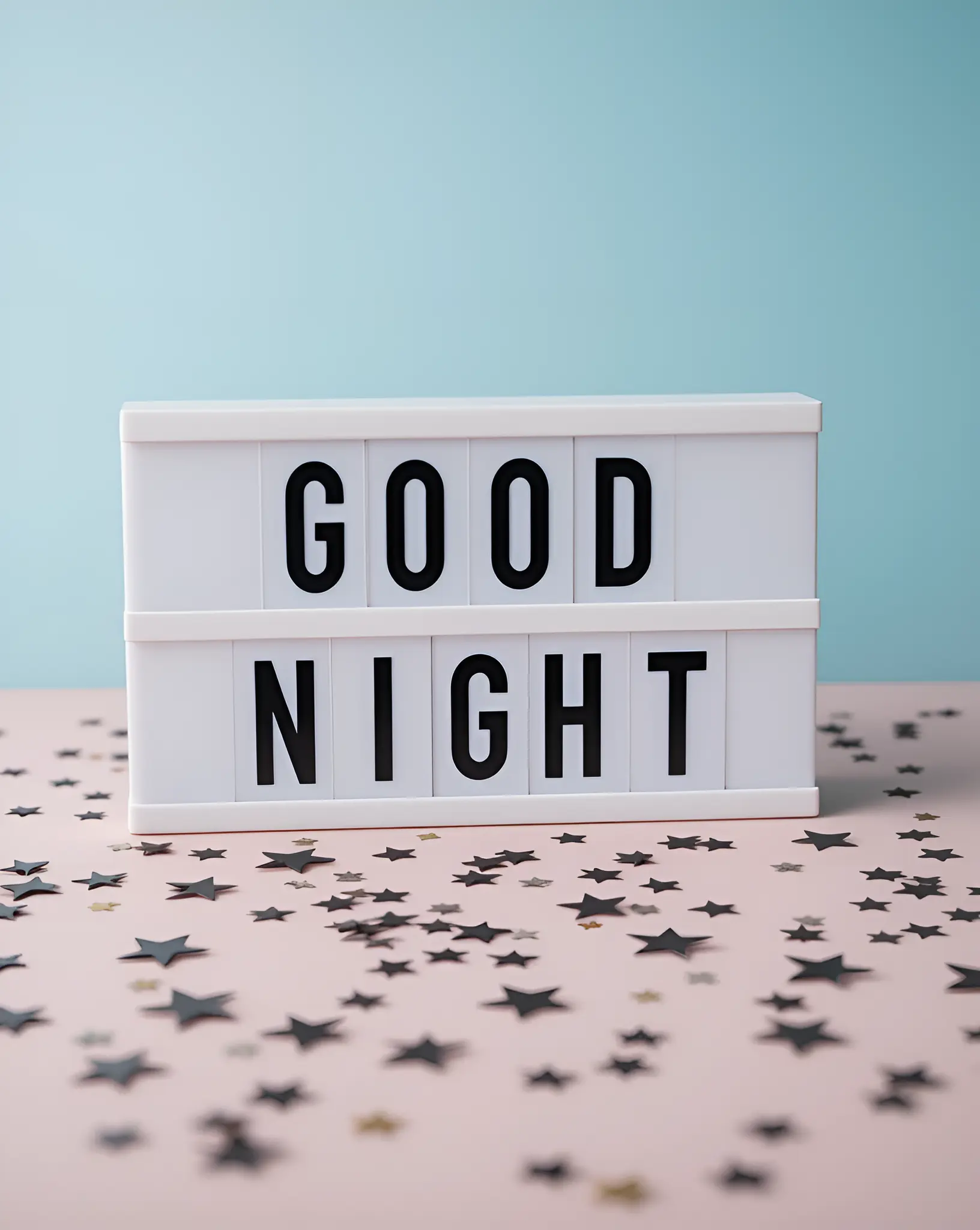 Illuminated Good Night Message on Lightbox with Star Confetti on Pastel Surface