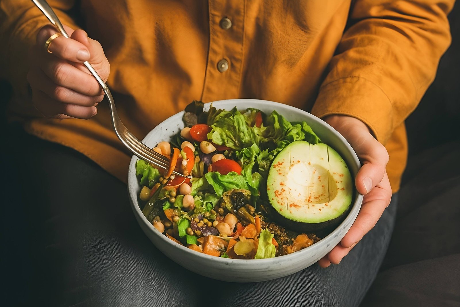 Person Eating a Nutritious Salad with Avocado and Fresh Vegetables