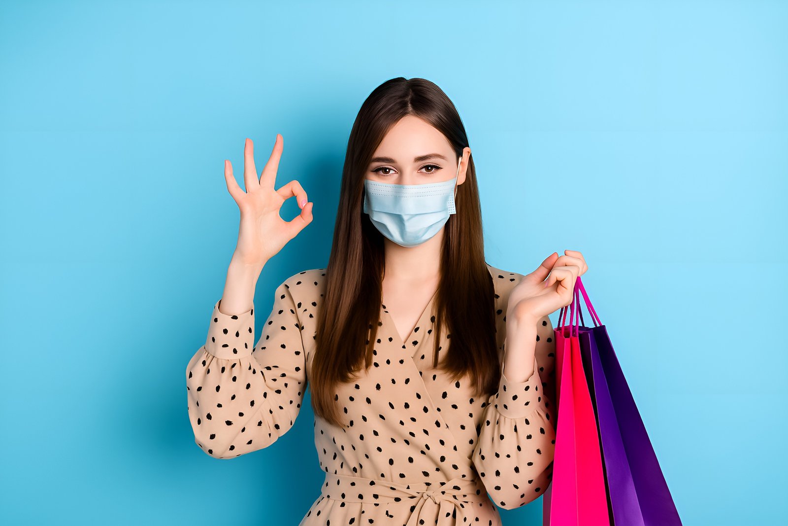 Woman Wearing Face Mask and Holding Shopping Bags Against Blue Background